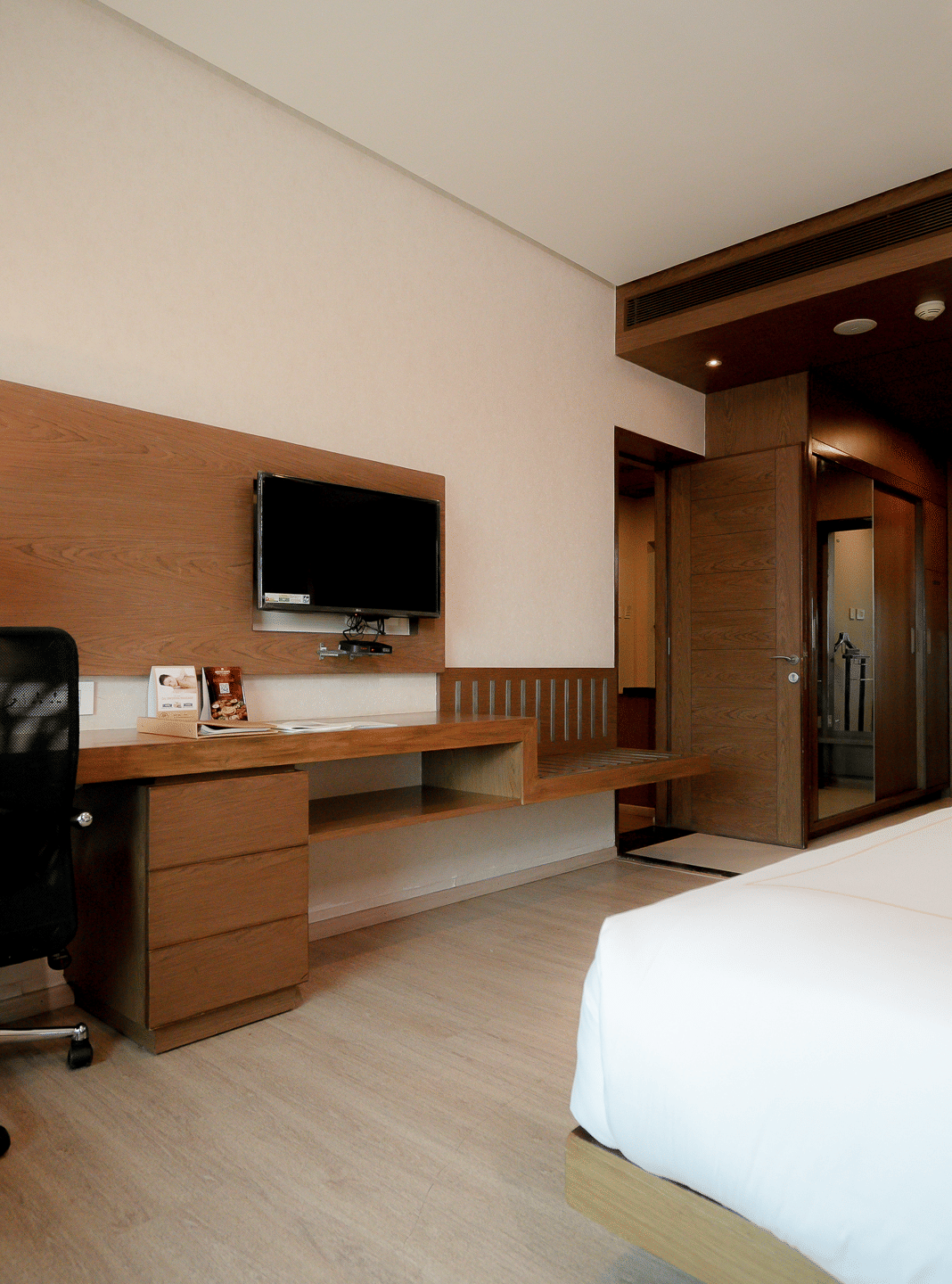 Modern room featuring a comfortable bed, work desk, and a flat-screen TV - Narayani Heights Hotel & Resorts