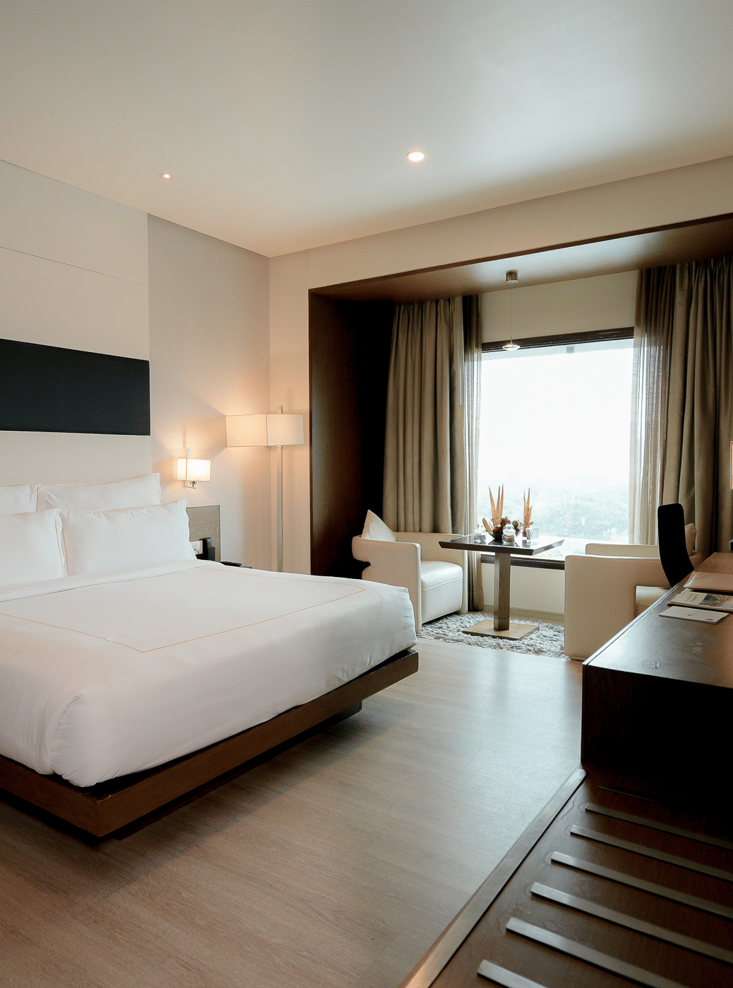 Modern hotel room with king size bed, large windows, seating area, and a work desk – Narayani Heights Hotel & Resorts