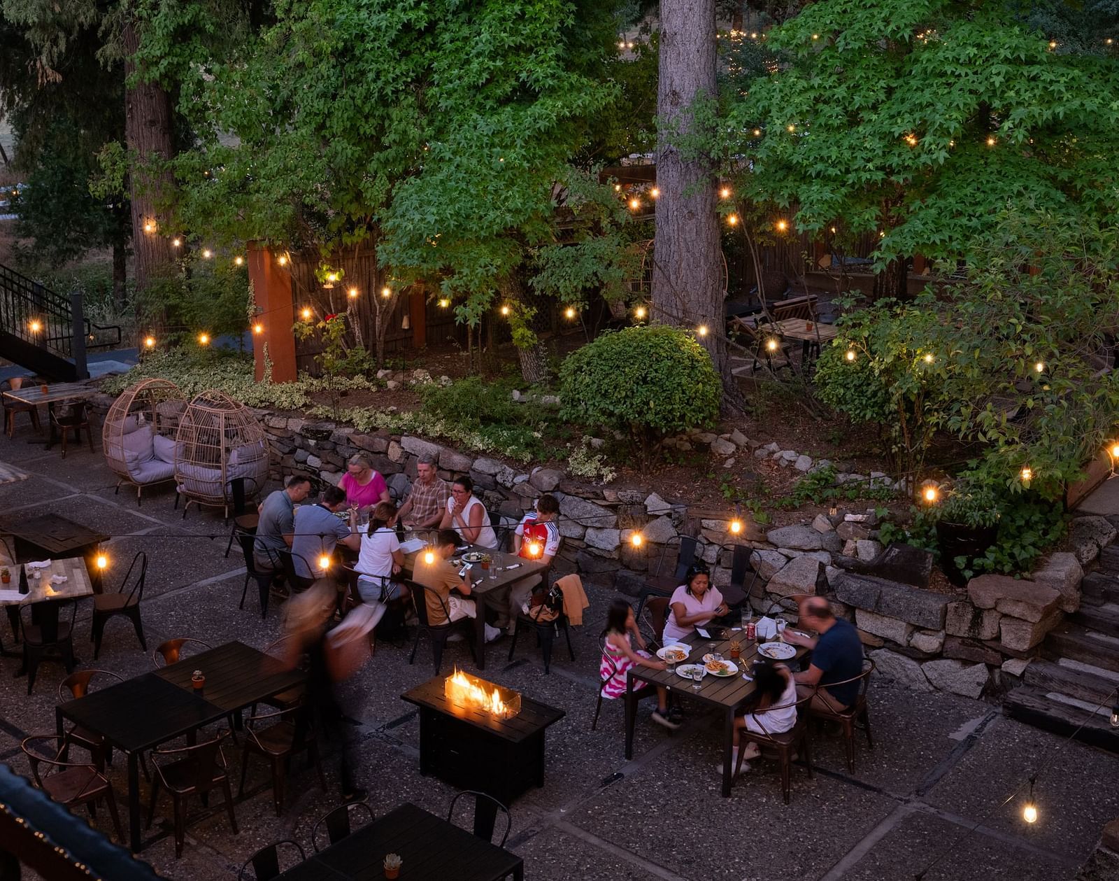Outdoor evening dining area with guests enjoying a meal under string lights at The Groveland Hotel.