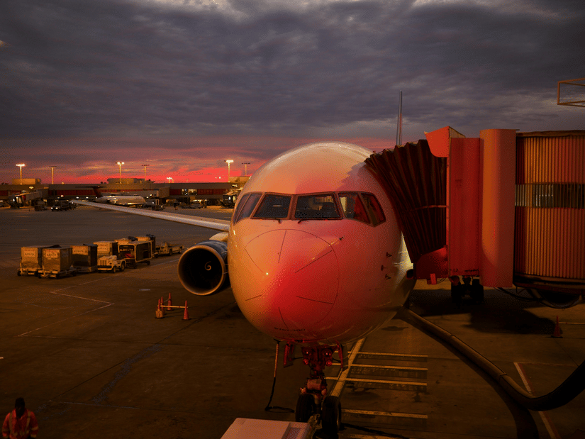 A close up shot of an aircraft during a late evening with the aerobridge attached.