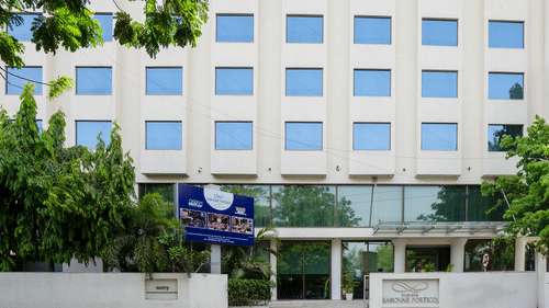  A facade image of the Marasa Sarovar Portico, Rajkot with trees around.