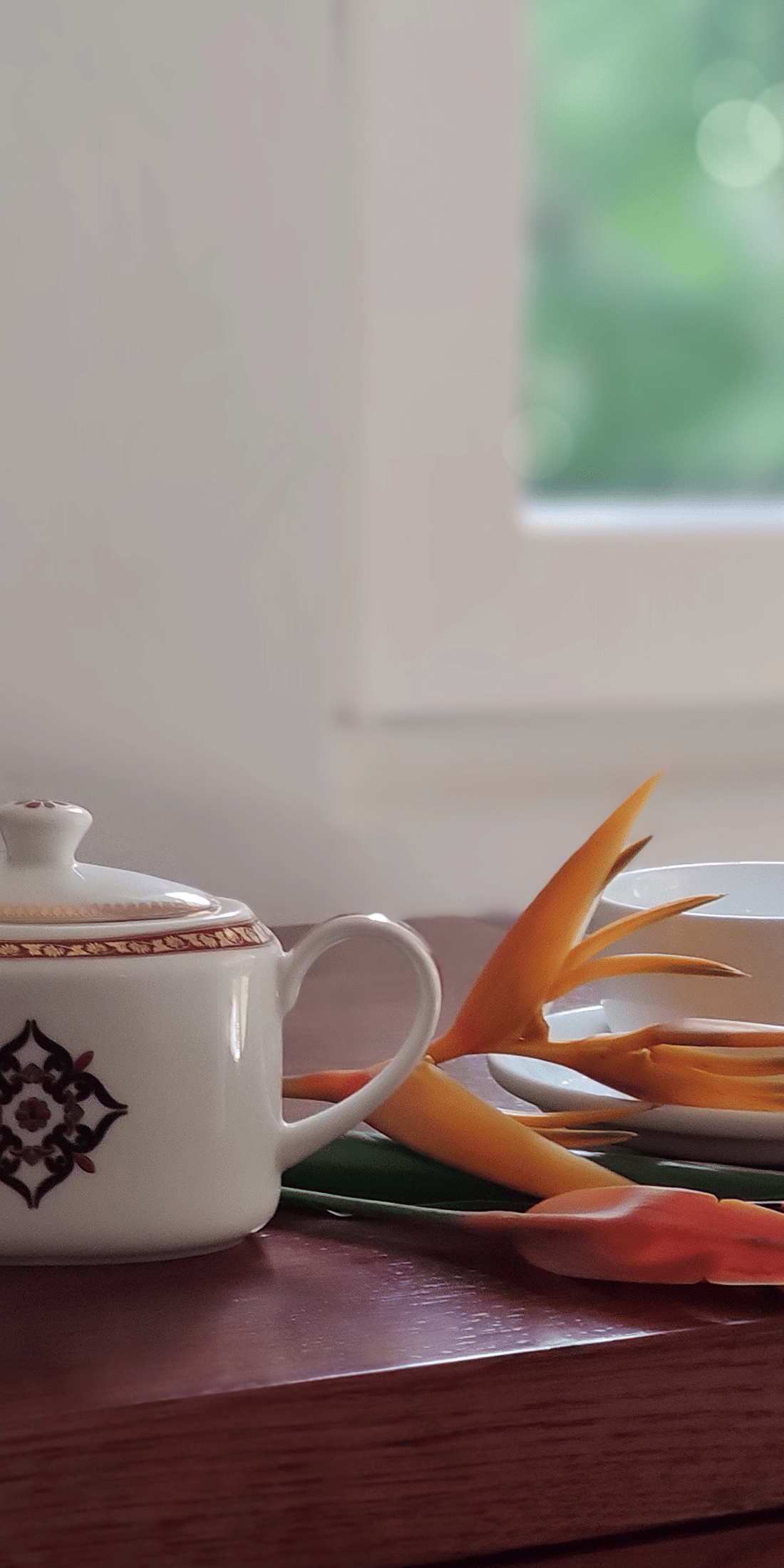 Teapot and cup on a table near a window with a flower-Amanvana Spa Resort, Coorg - Luxury Resort