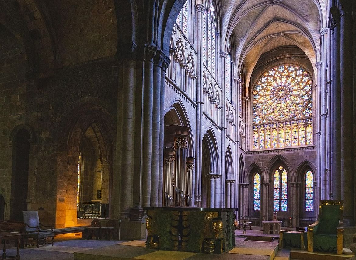  A gothic-style church interior showcasing high arches and a beautiful stained glass window, creating a serene atmosphere.