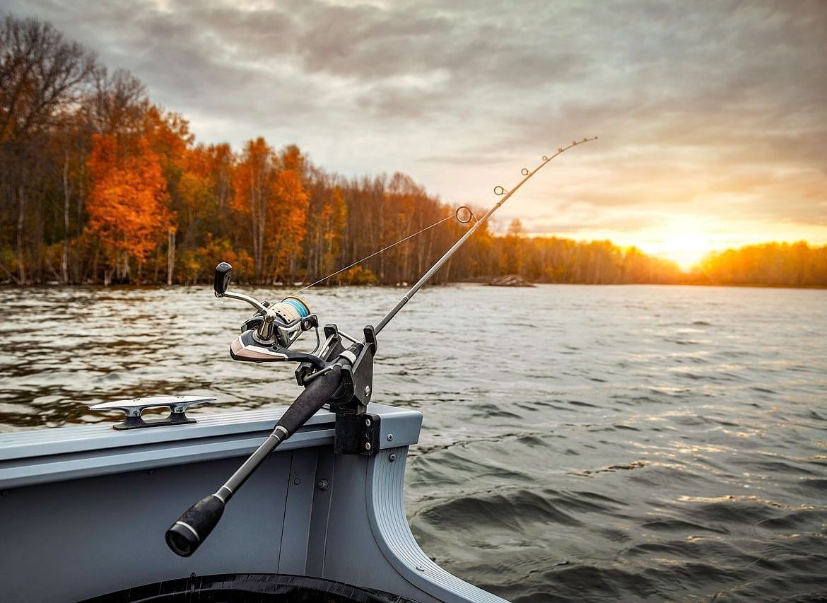  A scene of a fishing boat on calm waters, with the warm glow of a sunset and autumn foliage in the background.