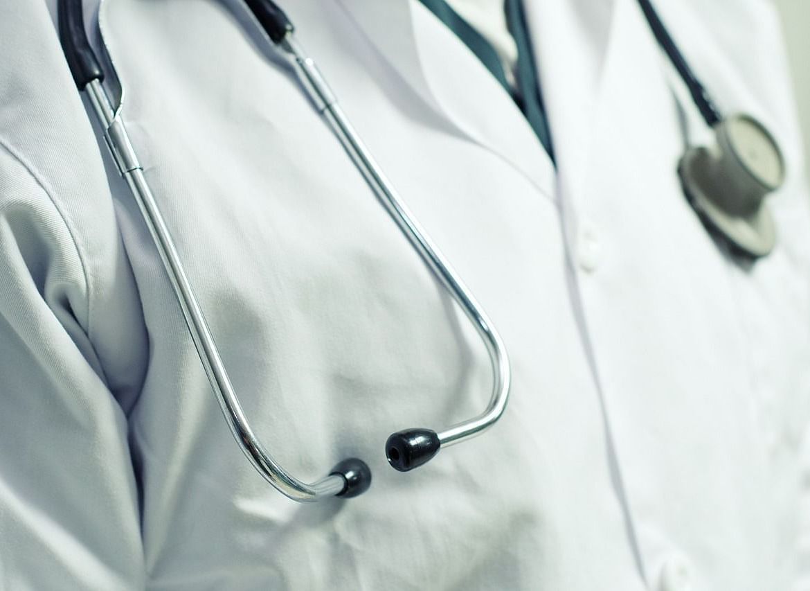 A close-up of a stethoscope hanging around the neck of a doctor wearing a white coat.