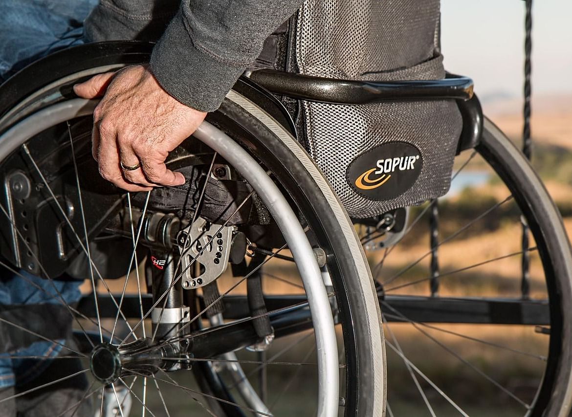 A close-up view of a wheelchair with a person's hand resting near the wheel