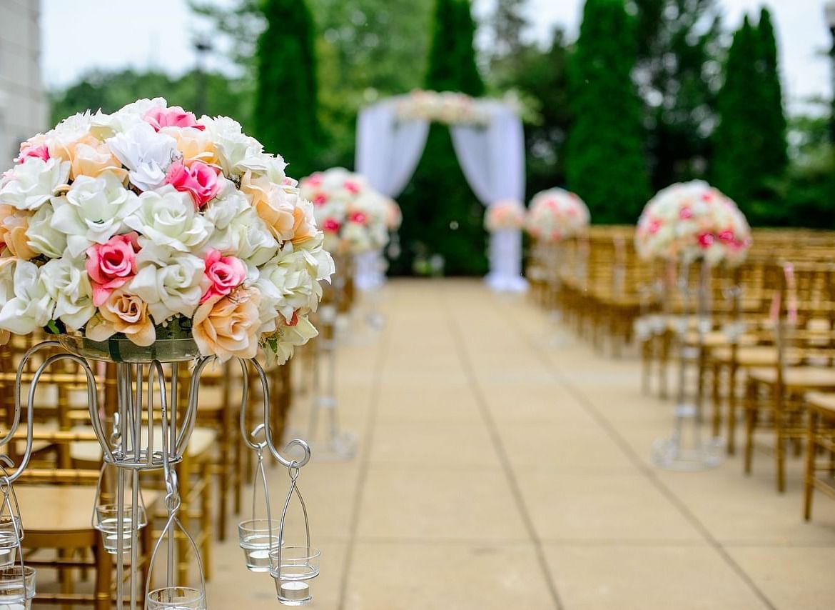 Elegant outdoor wedding ceremony setup with floral arrangements and an aisle.