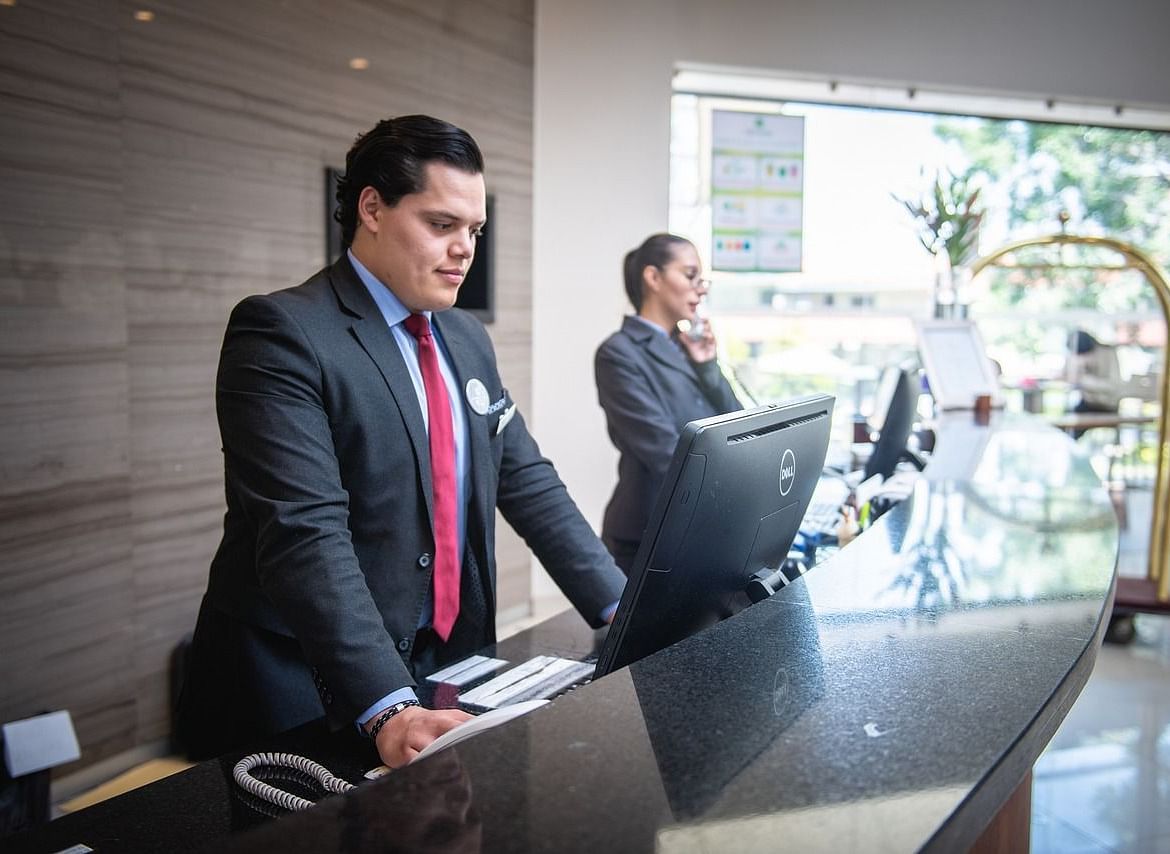 two people dressed in corporate formals on the reception desk looking at the monitor screen 