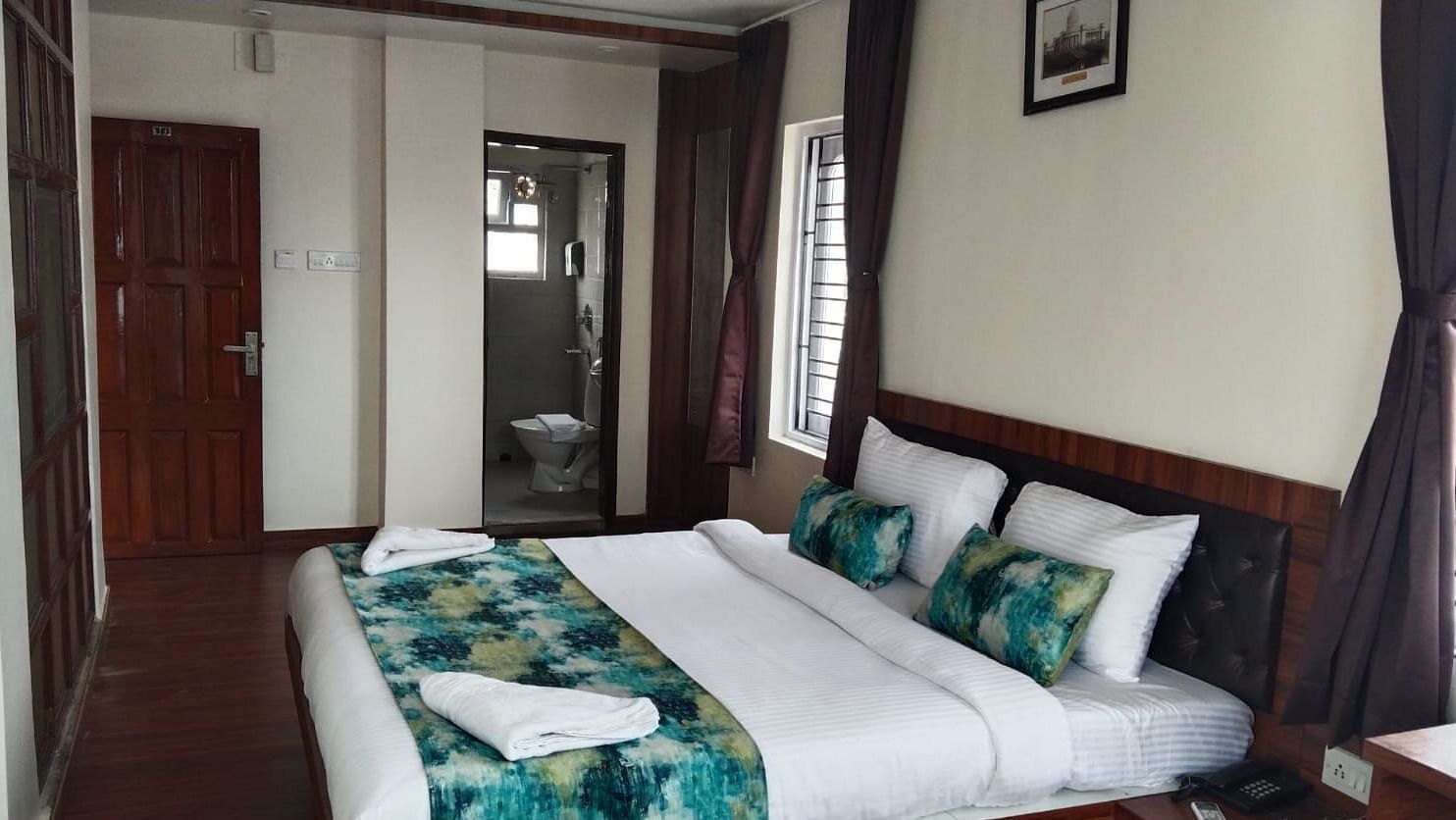 A double bed with towels kept on it inside the Deluxe room - Ecotel Kolkata