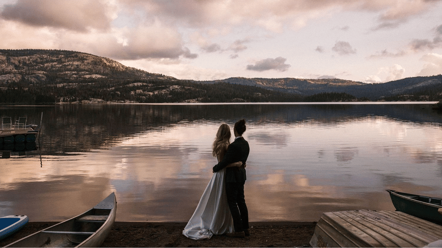 Couple standing by a serene lakeside during sunset with scenic mountain views in the background at Kit Carson Lodge.