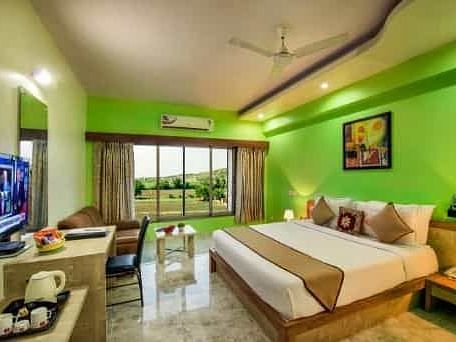 A brightly coloured room with a double bed, a television, and a balcony - Lion Lords Inn Rajula
