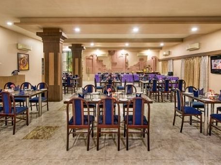 A large dining area is prepared with numerous tables and blue chairs - Lion Lords Inn Rajula