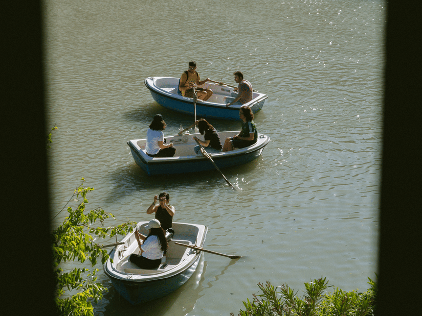A view from above of three boats on the river travelling in different directions with tree branches seen in the foreground.