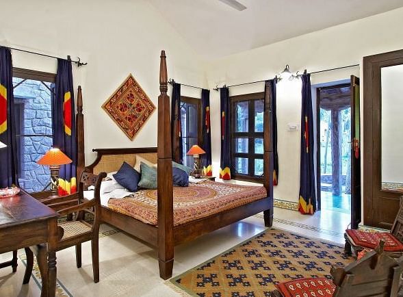An image of a room with a bed, bed side table, chairs, tables, lamps, ceiling fan and other decorative items - MANVAR Resort & Desert Camp