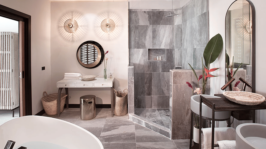 A vanity area with a mirror, a sink and a hamper at Tamarind Hills Resort and Villas, Antigua.