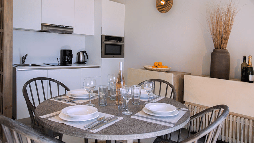A dining area with cutlery on a table, chairs, with a counter with appliances at Tamarind Hills Resort and Villas, Antigua.