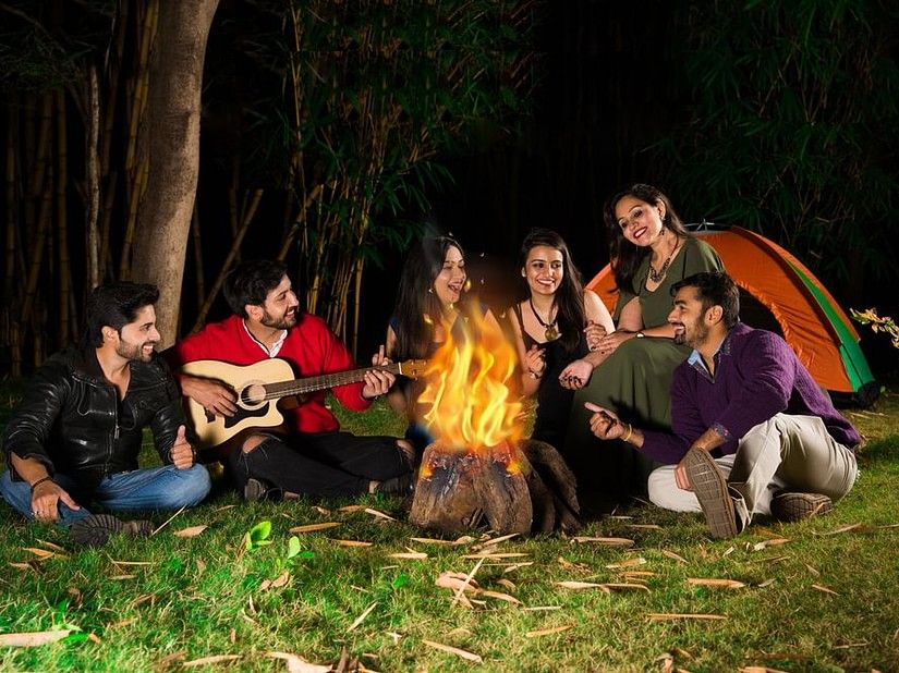 Group of Friends sitting in a circle around a fire camp