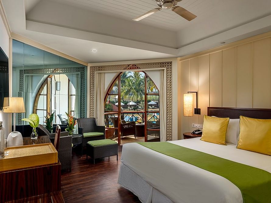 a double bed with a ceiling fan and a wall mounted tv inside Deluxe Room - Caravela Beach Resort Goa