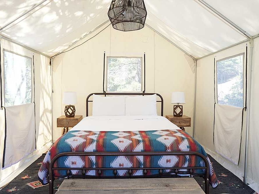 A tent with zip-down windows and a double bed placed in the middle at Shaver Lake Village Hotel.