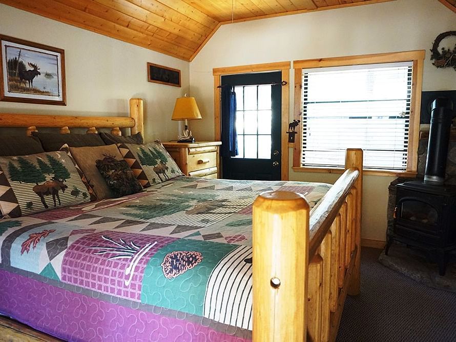 A room at Shaver Lake Village Hotel with a double bed with a colorful bedspread and a wooden ceiling.