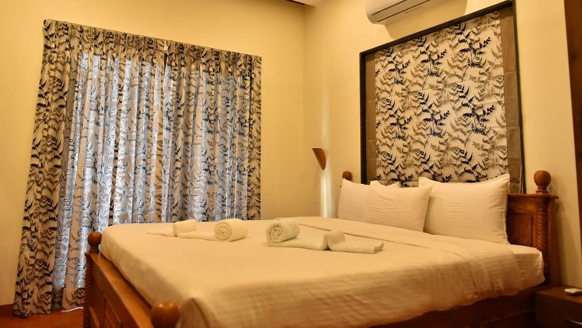 Cosy bedroom with a wooden bed, soft lighting, and patterned curtains, offering a warm and inviting atmosphere.