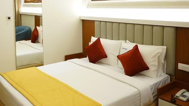 Room with a king bed, warm lighting, and artwork at Kalyan Residency Hotel, Tirupati – ideal for business or leisure guests.