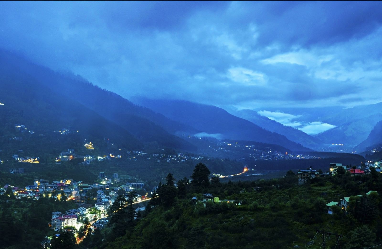 Birds eye view of a valley with lightsglowing from the town at the foothills of the mountain