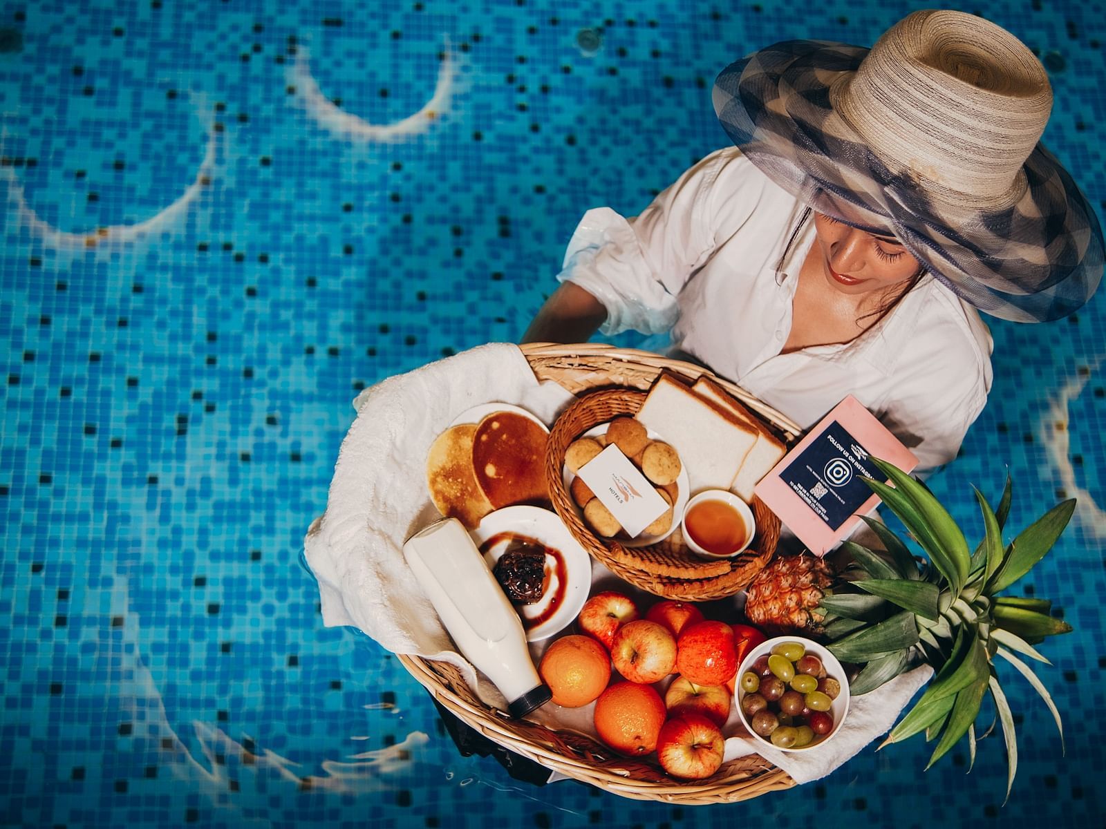 An overhead of a woman enjoying a dish with meat and vegetables in a swimming pool | Mansha Hotels