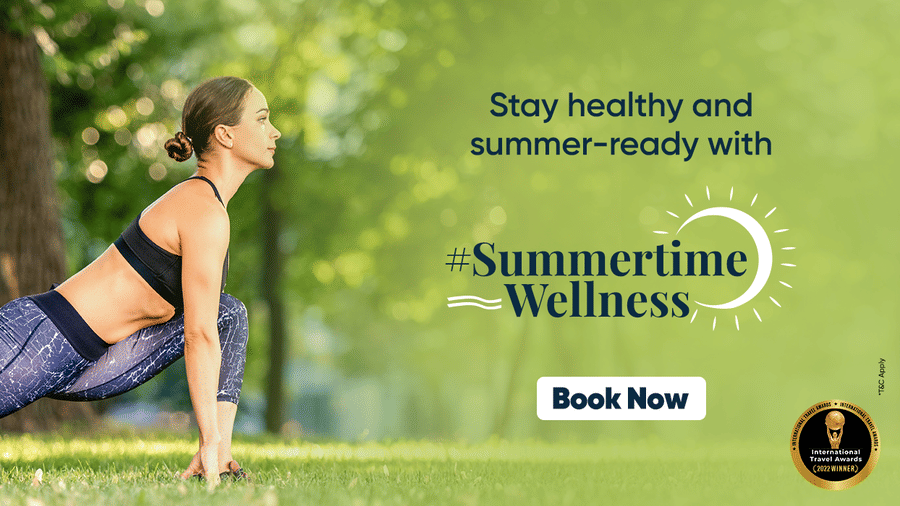 A woman practices yoga in a sunlit park, promoting a Summertime Wellness at YO1 Longevity & Health Resorts campaign with a call to action button that reads - Book Now