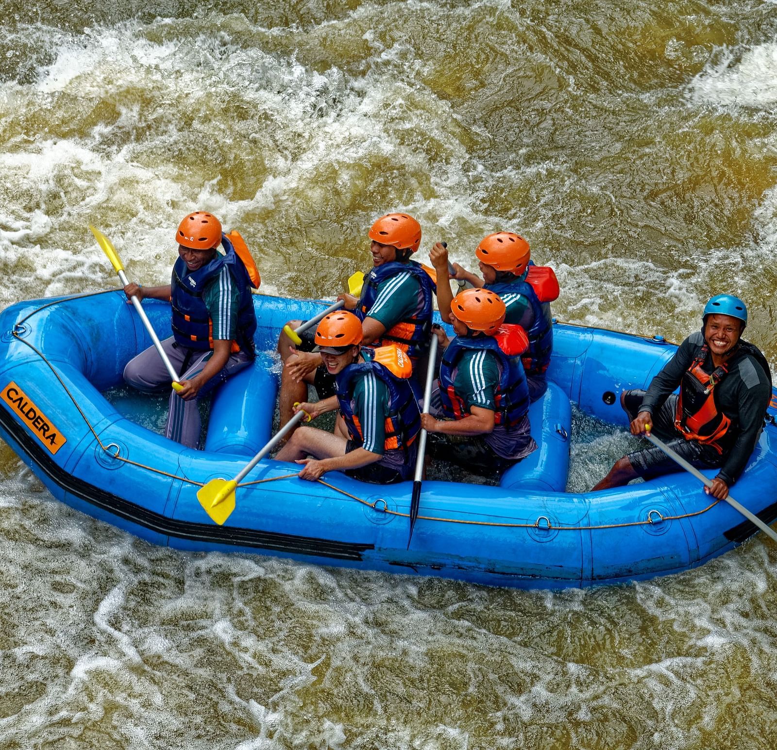 Group of people whitewater rafting in a raft.