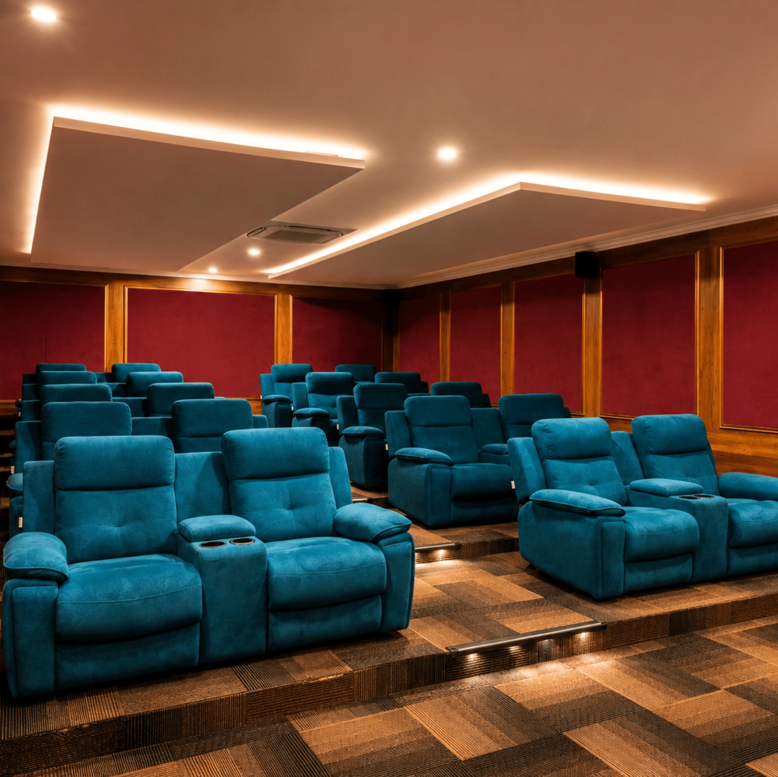 Box Office mini theatre with rows of teal recliner seats, padded red walls and cove ceiling lighting at MAYFAIR Palm Beach Resort, Gopalpur-on-Sea.
