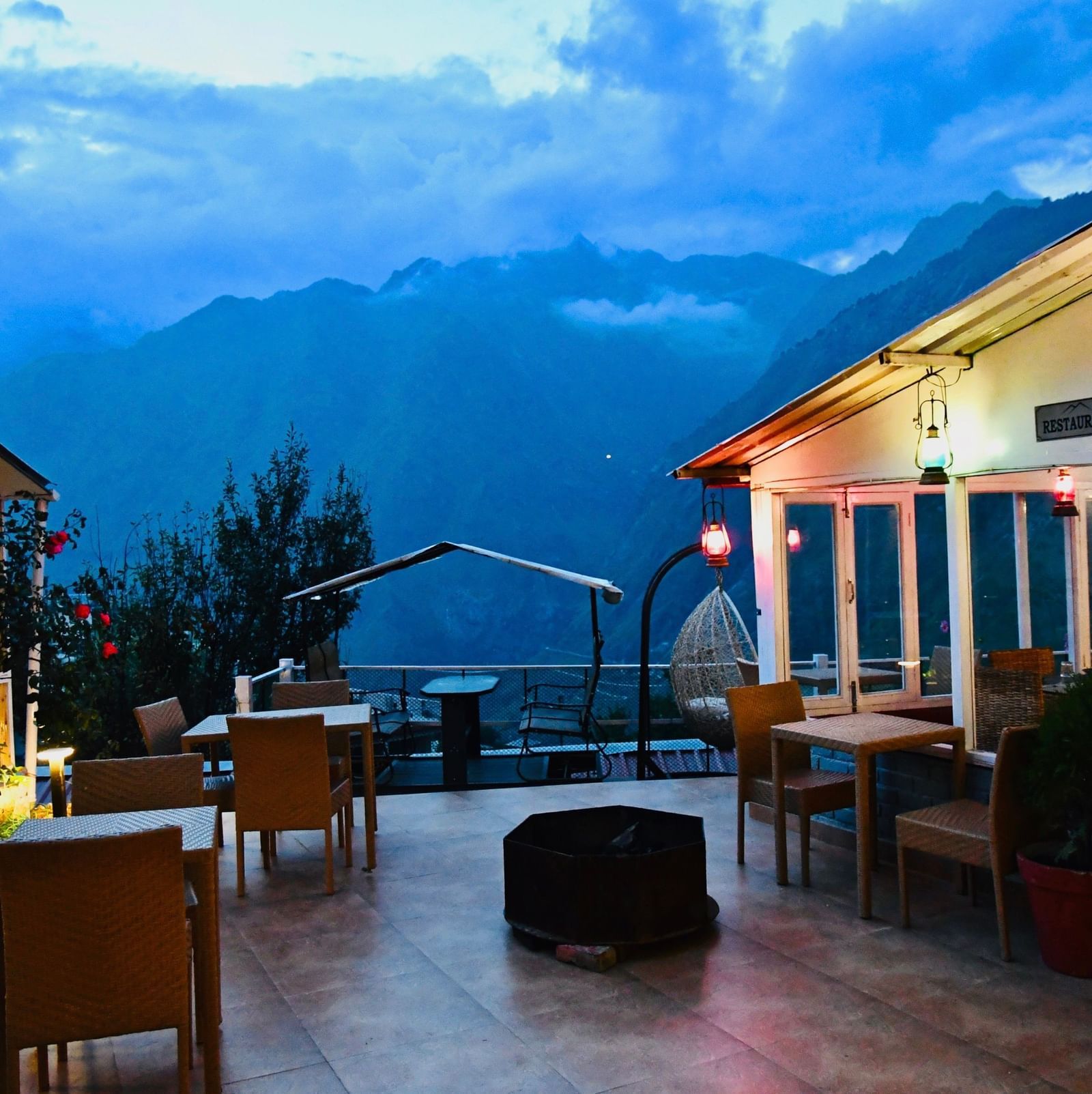 image of the outdoor seating area at the tattva, joshimath with beautiful mountain landscapes in the background on a late evening