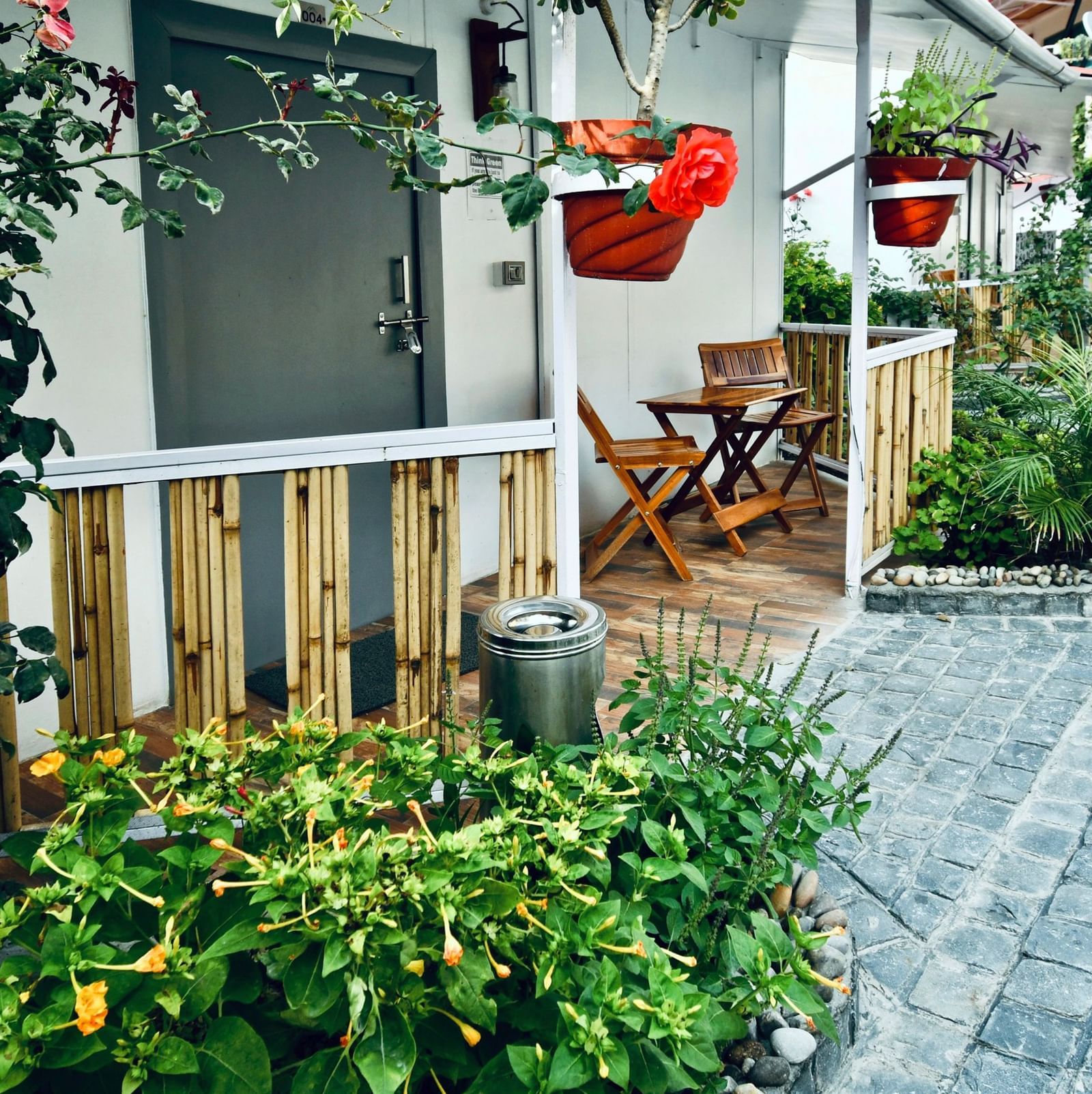 image of a porch lined with beautiful green plants with an outdoor seating area - The Tattva, Joshimath