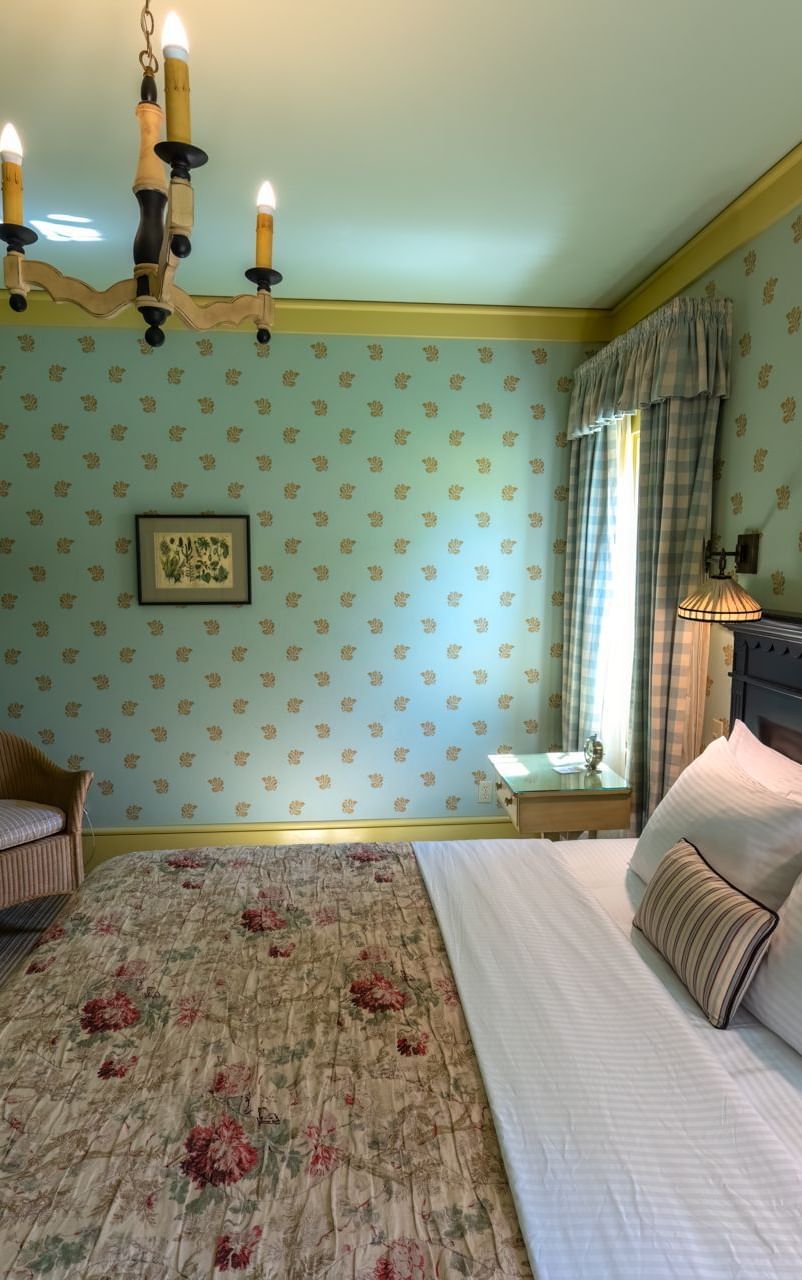 Side view of one of the accommodations at Tallman Hotel in Groveland, showcasing ample space, plush bedding, and a rustic wardrobe.