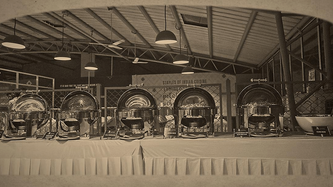 Black and white photo of a buffet setup with chafing dishes in a large space.
