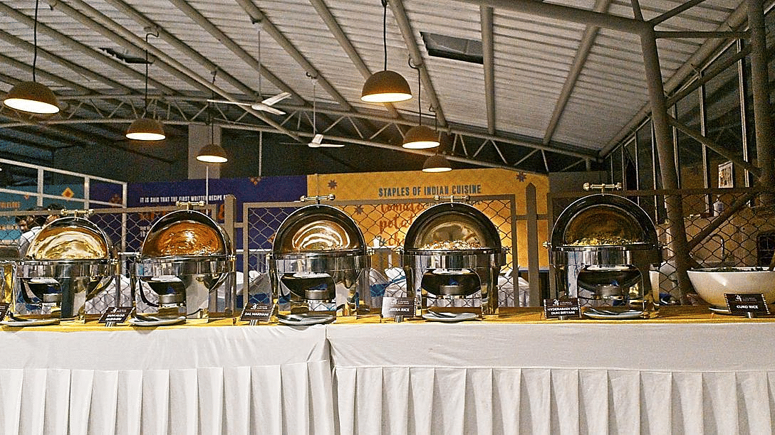 Buffet setup with chafing dishes under bright industrial lighting in a large space.