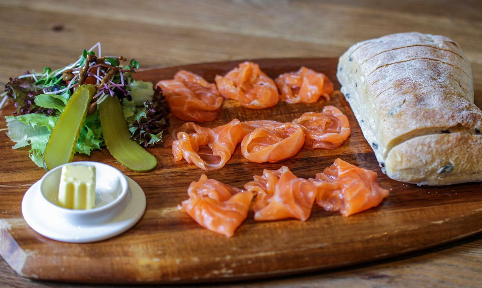 A wooden board displays smoked salmon, cream cheese, bread, and greens | The Shop | Central Mansions, Phnom Penh