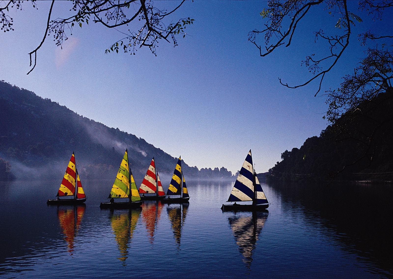 Colorful paddleboats on a lake at sunset.