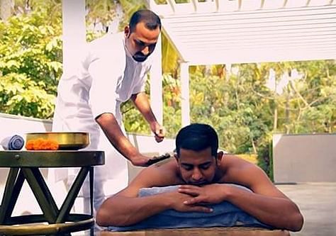 A person receiving a massage on a table outdoors, with another person standing - Shreyas Retreat
