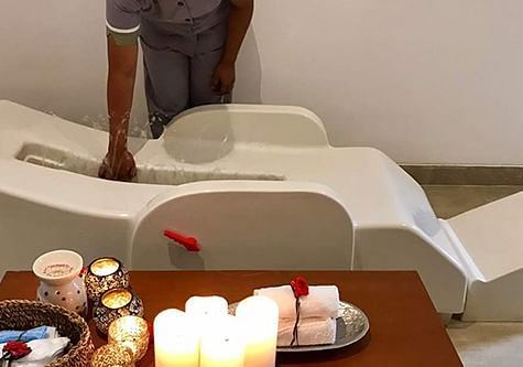 A white chair with candles and items on a tray, indoor setting - Shreyas Retreat