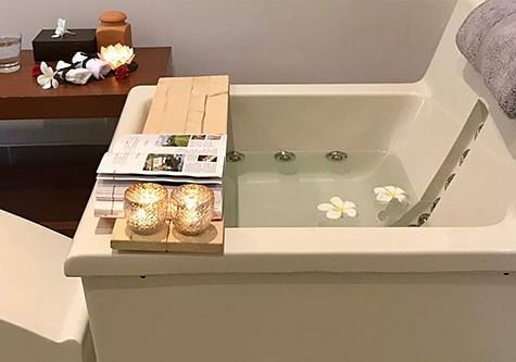 A bathtub with items arranged on a wooden tray, indoor setting - Shreyas Retreat