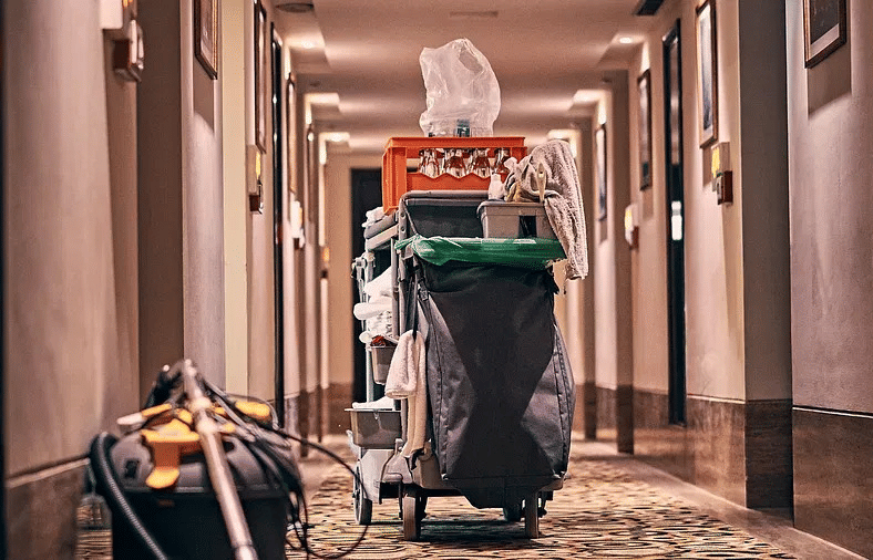 A housekeeping trolley with cleaning supplies placed in a hotel corridor.