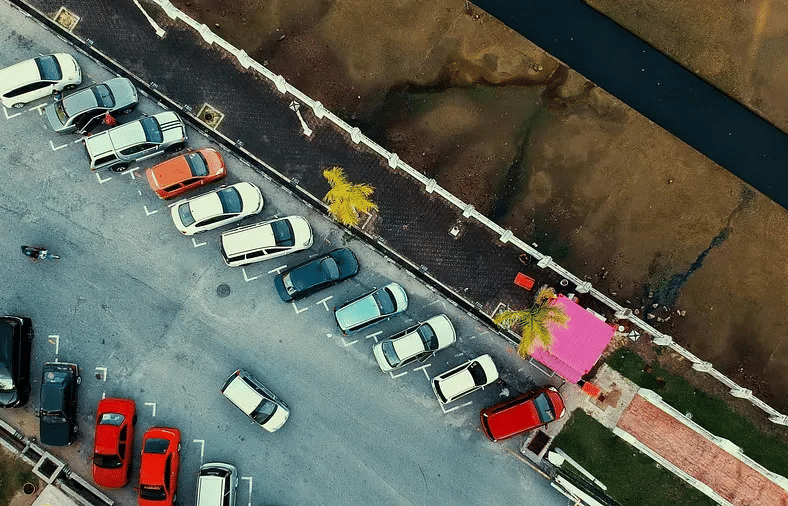 An aerial view of a parking lot with several cars parked in designated spots.