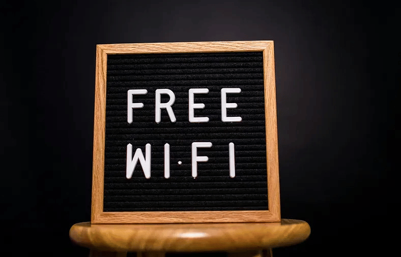 A chalkboard sign placed on a wooden stand displaying 'Free Wi-Fi'.