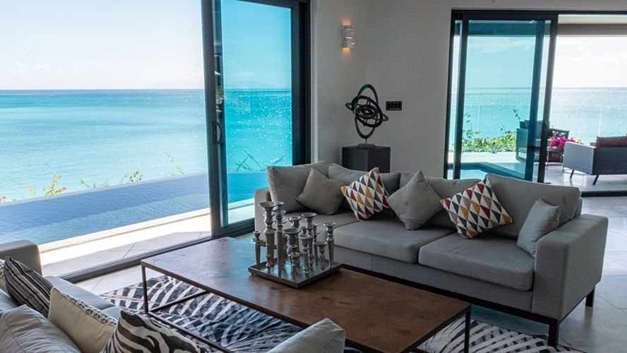 Luxury villa living room at Tamarind Hills Resort and Villas Antigua with open glass doors framing ocean views.