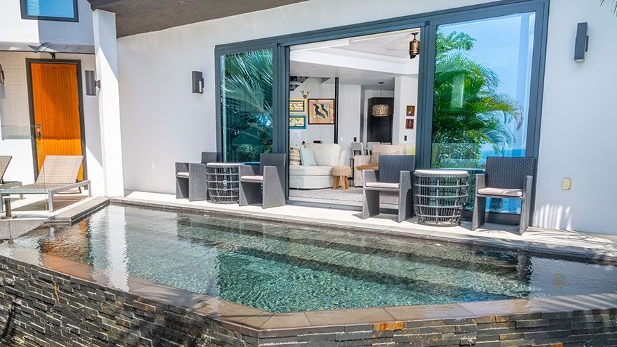 Contemporary villa patio with a stone-edged plunge pool and shaded outdoor dining area at the background.