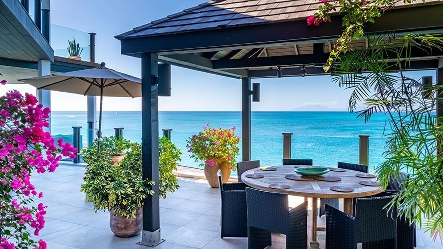 A charming outdoor dining area by the sea, surrounded by vibrant flowers and serene blue views - Tamarind Hills Resort and Villas - Antigua