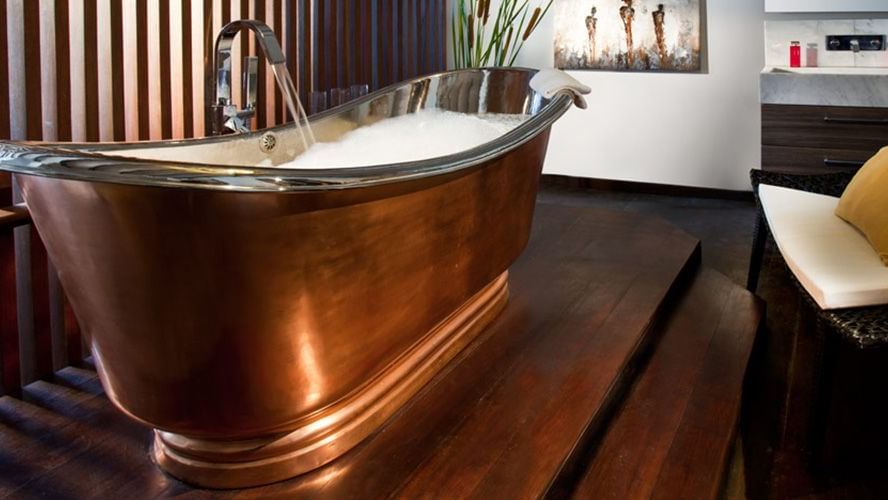 Image of a brass bathtub filled with water.