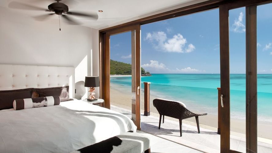 A serene beachfront bedroom with floor-to-ceiling glass doors, offering breathtaking views of turquoise Caribbean waters - Tamarind Hills Resort and Villas - Antigua