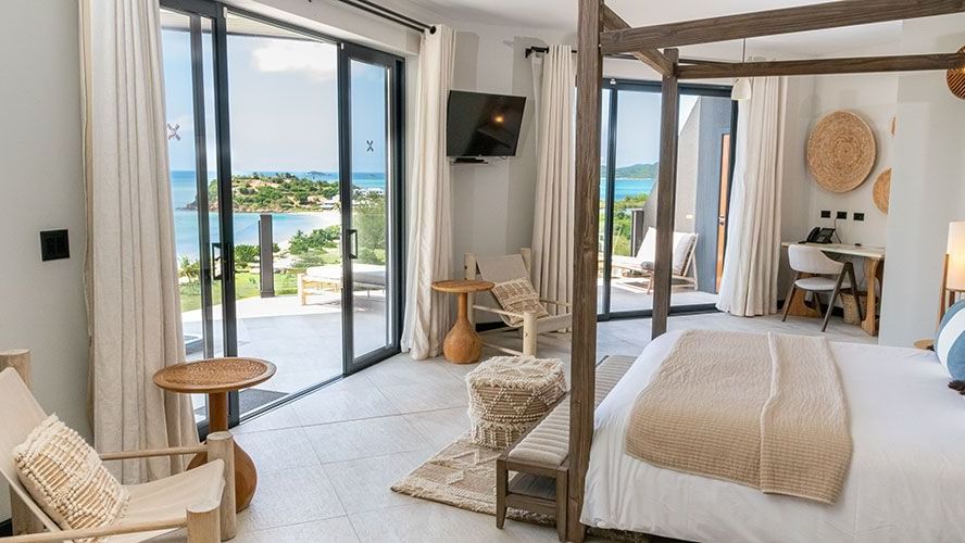 Cozy, ocean-view Tamarind Suite offers a stunning vistas of the sea outside and curated Bohemian furniture inside with a double bed facing the TV and the sea, a work desk, a chair and a sliding door that leads towards the sea. -Tamarind Hills Resort and Vi